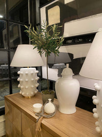 White alabaster teardrop fat bottom vase on table with other décor and art